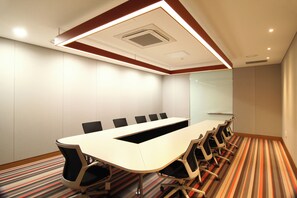 Una sala conferenze con un lungo tavolo, sedie e una moquette decorata.
