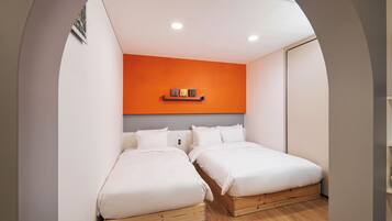 Un dormitorio con dos camas, una pared de acento naranja y suelo de madera.