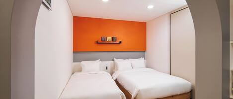 Un dormitorio con dos camas, una pared de acento naranja y suelo de madera.