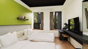 A modern hotel room with a bed, desk, TV, and large windows.