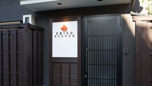 Una puerta de madera con un letrero que dice "EBISU RYOKAN".