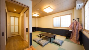 Una habitación japonesa tradicional con suelo de tatami, una mesa baja de madera, cojines y un puertas correderas.
