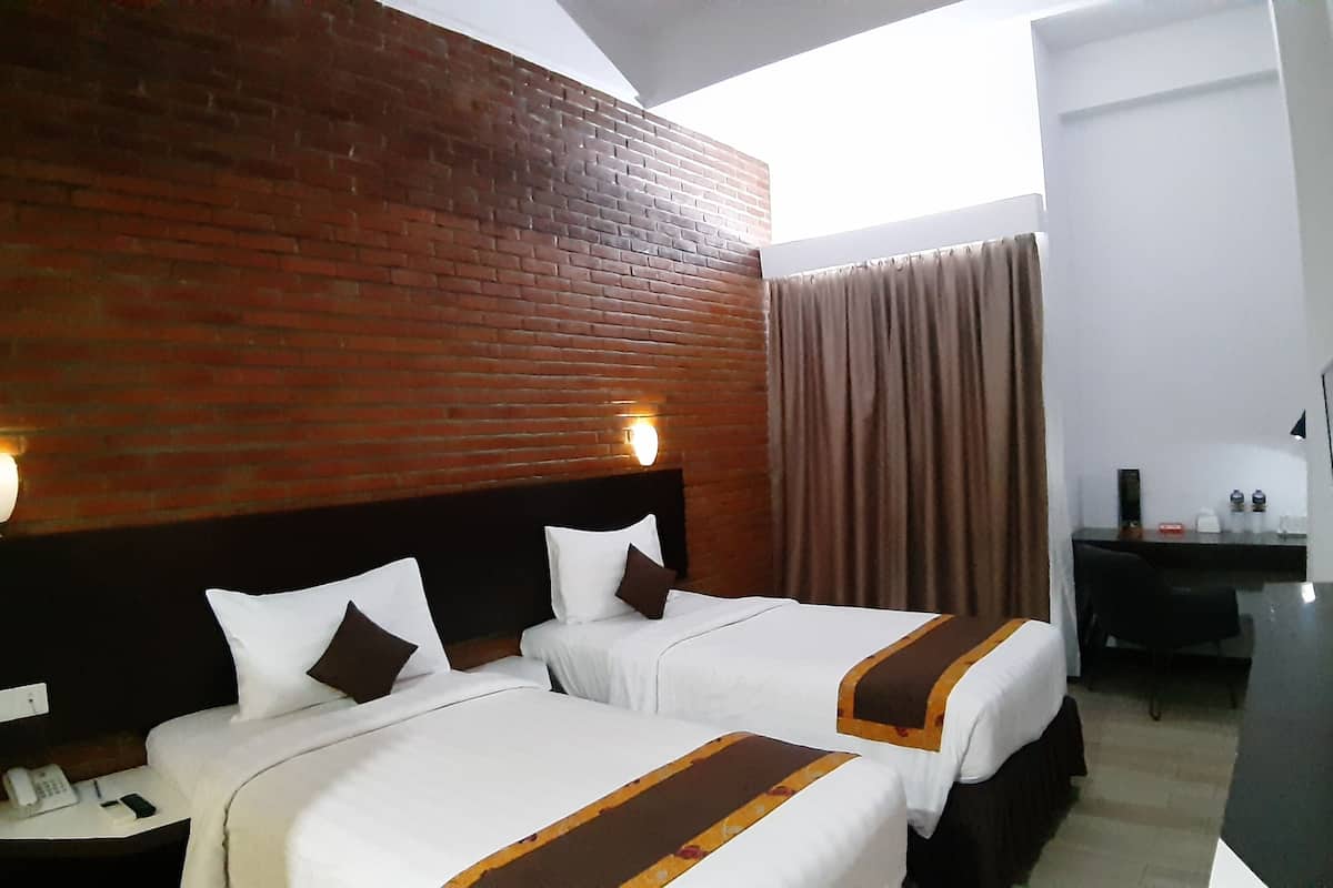 Ein Hotelzimmer mit zwei Betten, einer Ziegelwand, einem Schreibtisch mit Telefon und Blick zum Himmel.