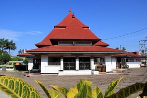 A building with a red roof and white walls, featuring a central entrance and a small porch area.