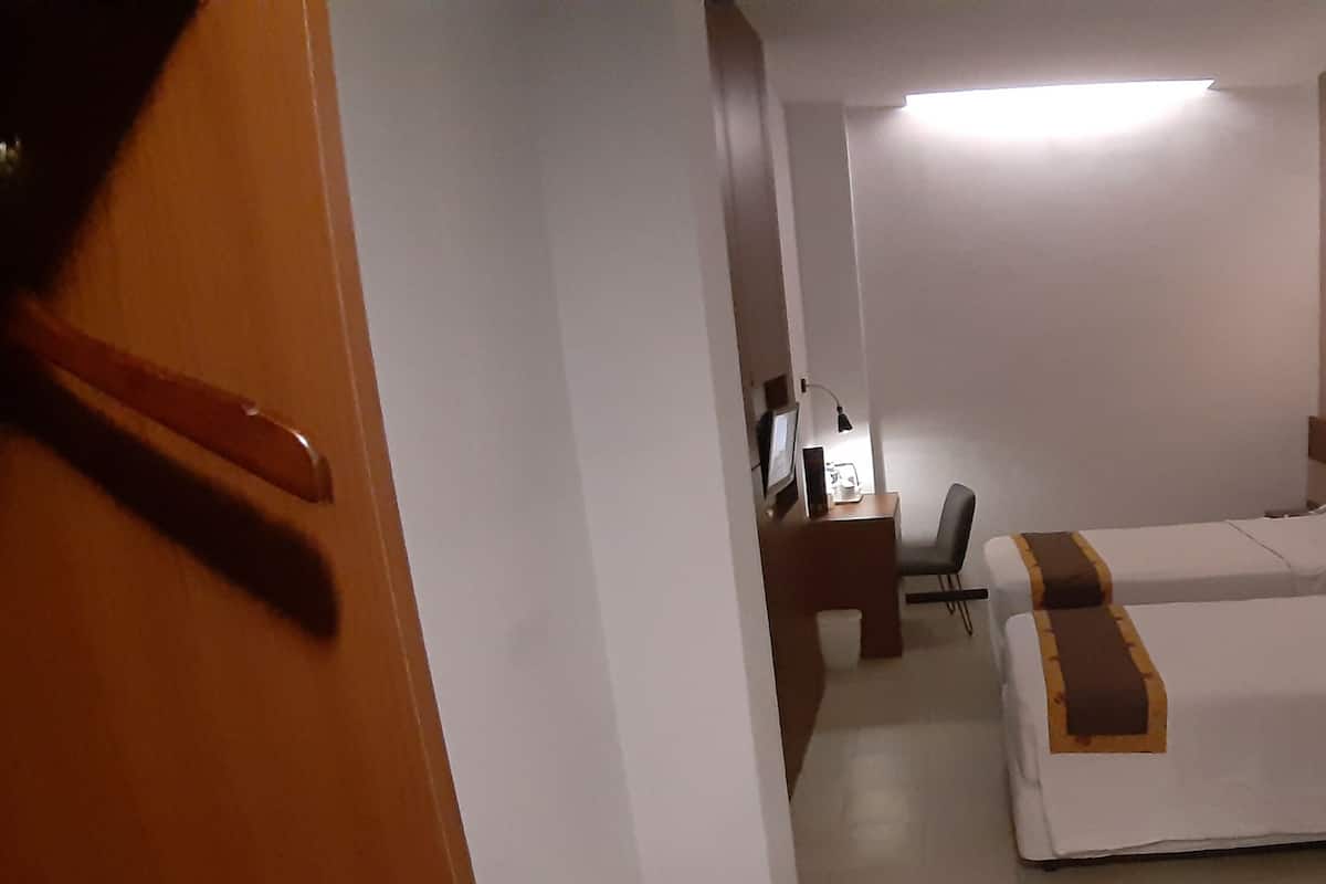Ein Hotelzimmer mit zwei Betten, einem Schreibtisch, einem Stuhl und einem Nachttisch.