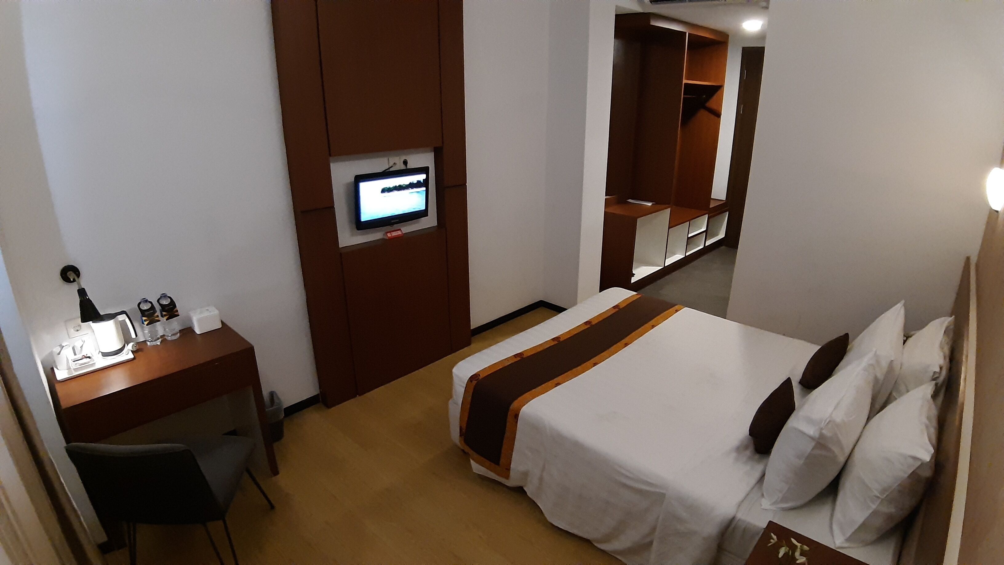 Une chambre d’hôtel comprenant un lit, un bureau avec un ordinateur, une télévision et une armoire.