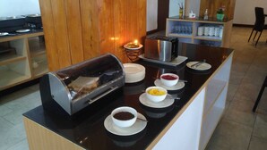 Une cuisine moderne équipée d’une machine à café intégrée, d’un grille-pain et d’un petit réfrigérateur.