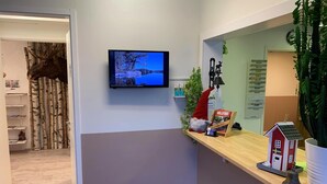 A reception area with a mounted TV displaying a scenic landscape, a small gnome decoration, a wooden sign, and a miniature house model. - Hällefors Vandrarhem & Kanotcenter - Hostel (Hallefors)