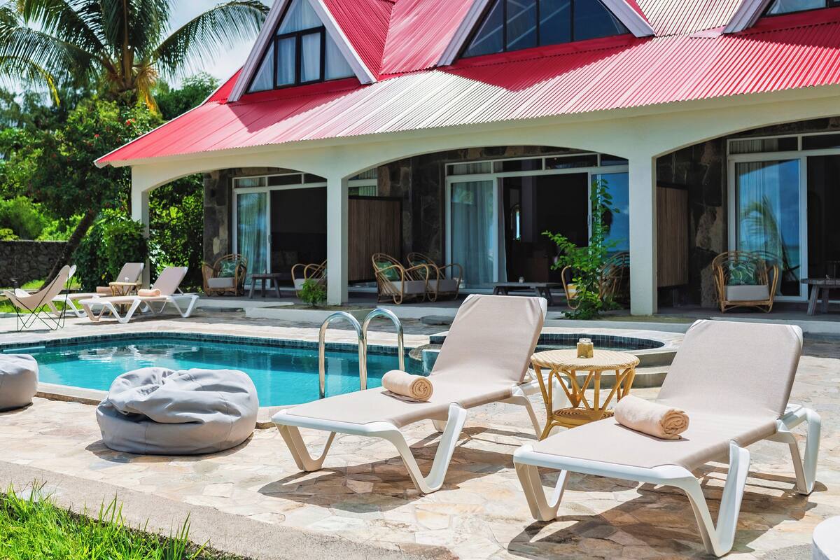 Un área junto a la piscina con sillones de descanso.