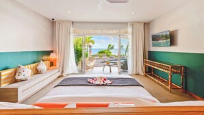 Una habitación de hotel con cama, sofá, televisión y balcón con vista al océano.