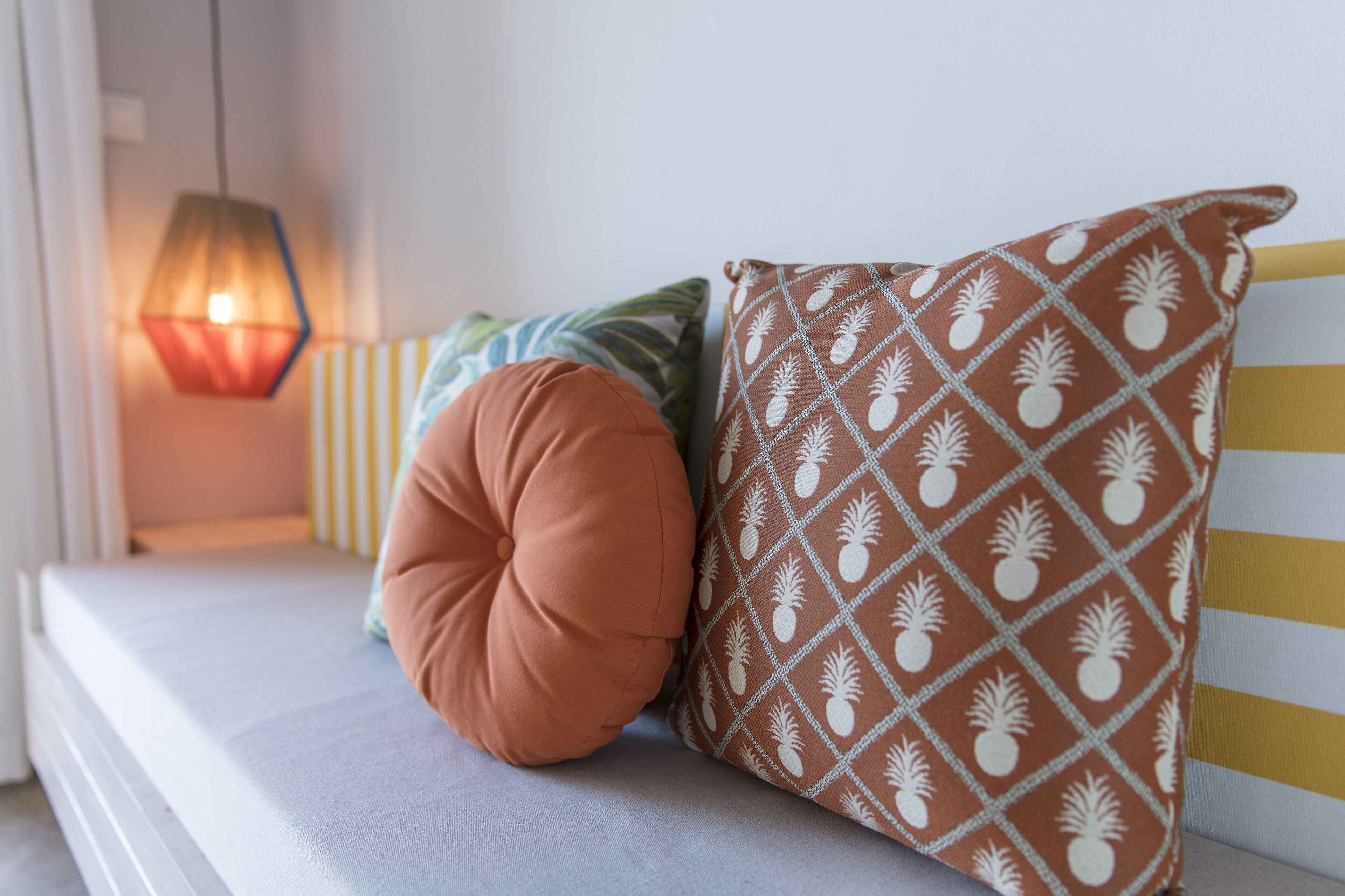 Un espace détente avec un banc rembourré, un coussin à motifs et un luminaire suspendu.