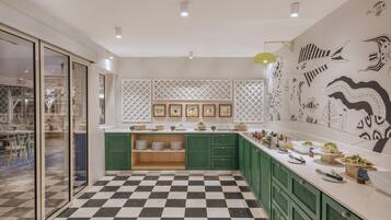 A modern kitchen with green cabinets, a checkered floor, and a wall decorated with fish illustrations.