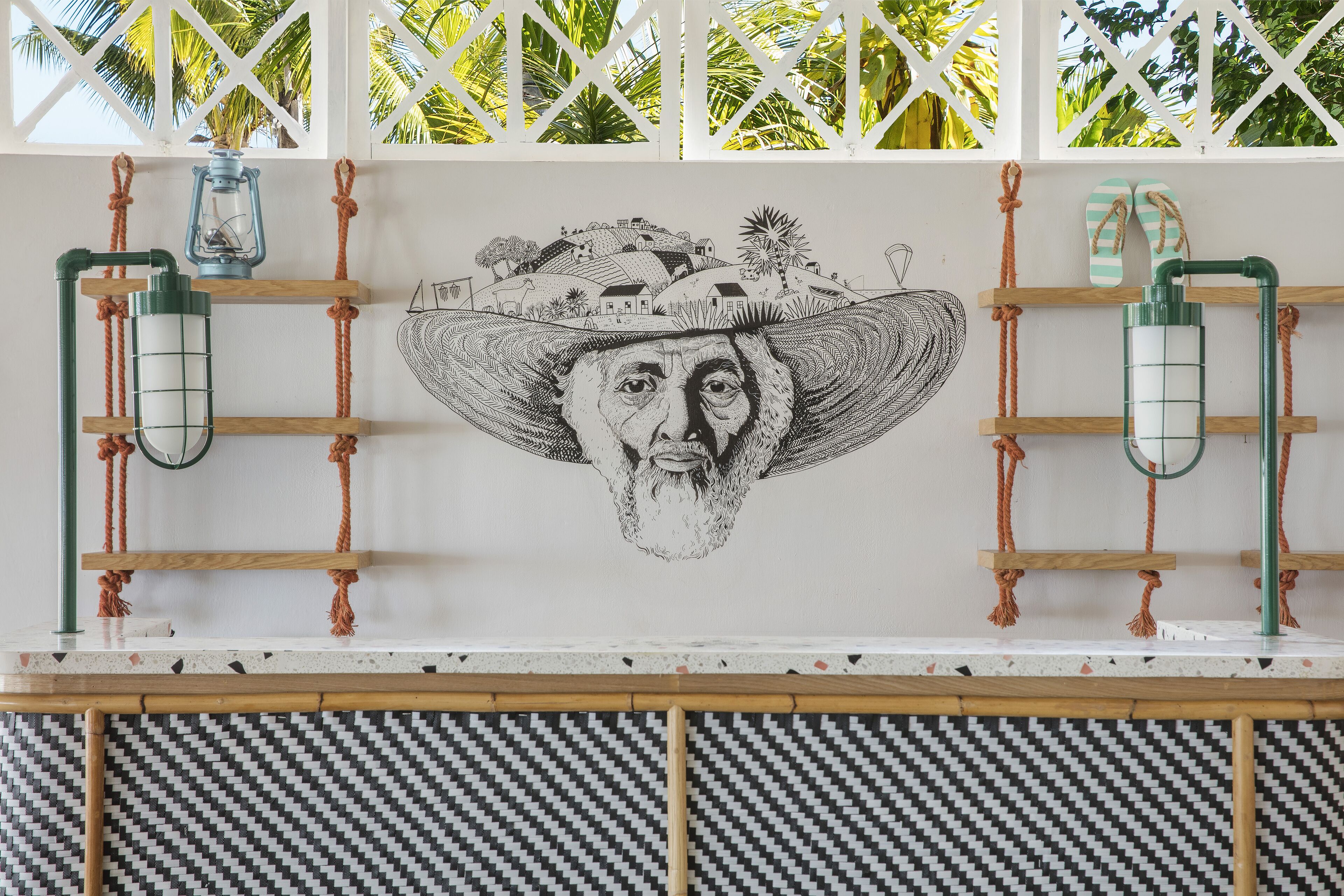 A wall with a mural, two lanterns, and a pair of sandals.