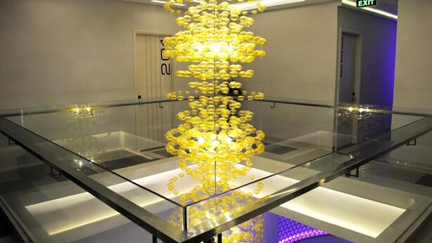 A modern interior with a central glass table reflecting a chandelier made of yellow spherical lights. - VIO Westhoff (Bandung)