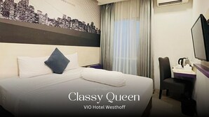 A hotel room with a bed, a cityscape mural, a window with curtains, an air conditioning unit, a desk with a chair, and a television. - VIO Westhoff (Bandung)