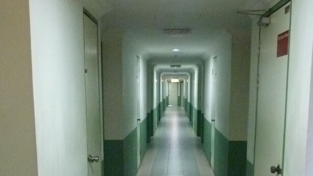A long, narrow hallway with doors on both sides, leading to individual rooms. - Hotel Hung Hung (Kuching)