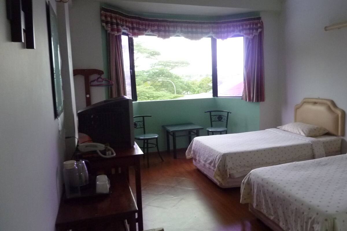 A room with two beds, a desk, a chair, and a television.