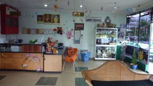 A reception area with a counter, chairs, a wicker sofa, and a display cabinet. - Hotel Hung Hung (Kuching)