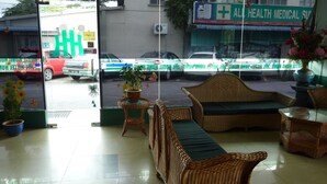 A reception area with wicker furniture, a potted plant, and a view of the street outside. - Hotel Hung Hung (Kuching)
