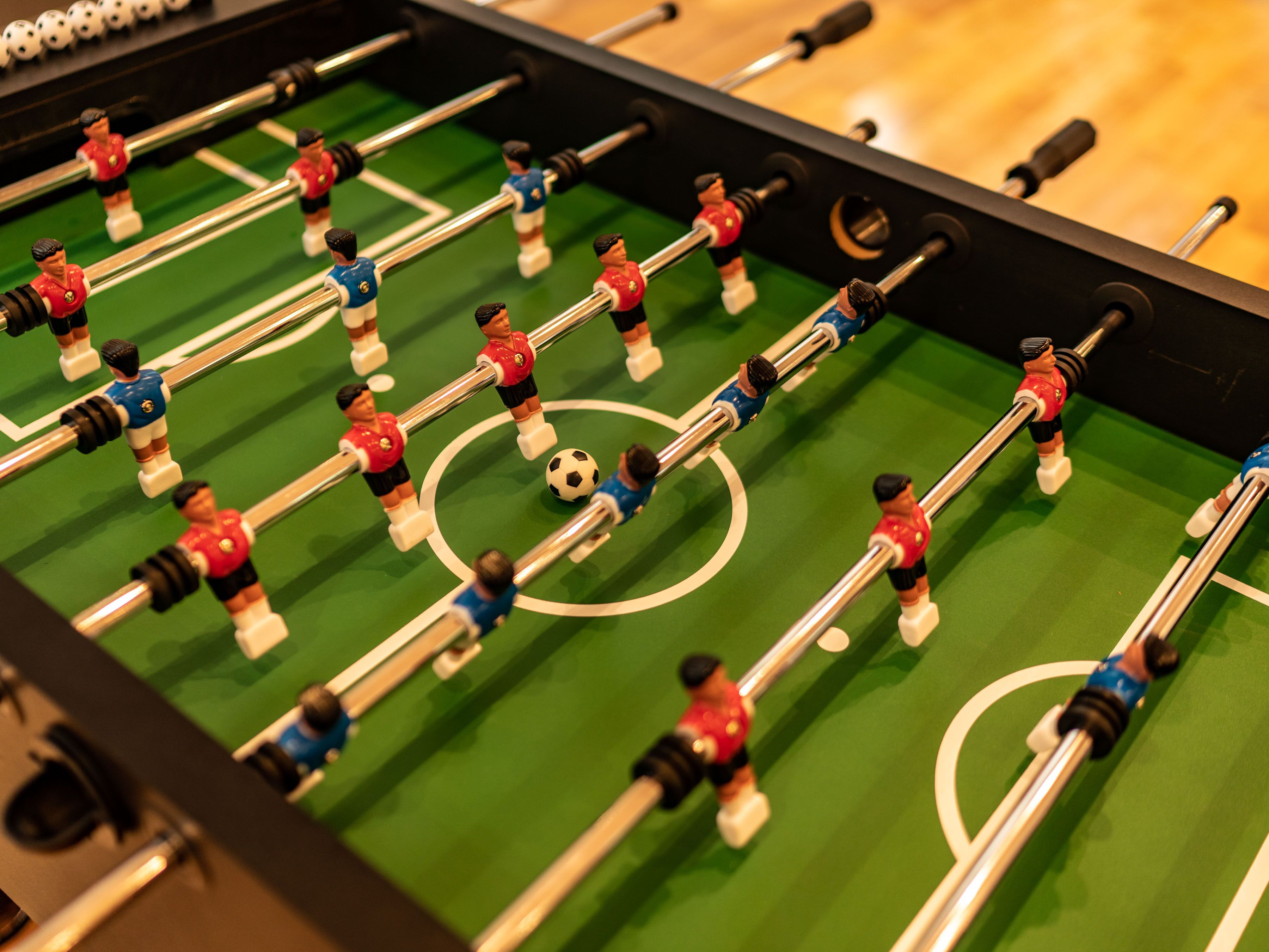 A close-up of a foosball table with figures in red and blue uniforms.