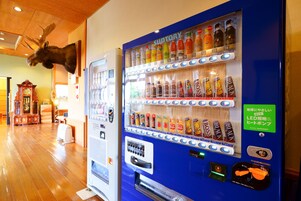 A vending machine with various drinks and snacks, a clock, and a moose head decoration.