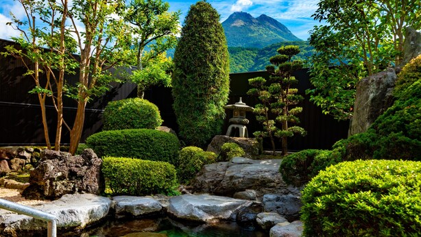 Un jardín tranquilo con un estanque cristalino, formaciones rocosas y una pagoda.