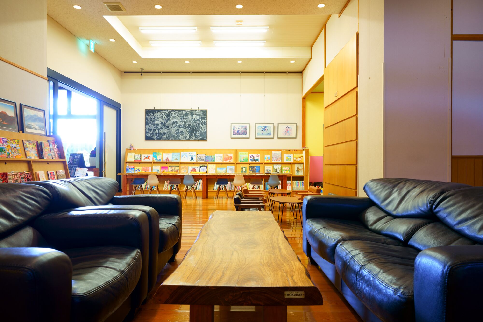 Una biblioteca con sofás de cuero, una mesa de madera y estanterías repletas de libros.