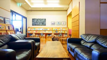 Una biblioteca con sofás de cuero, una mesa de madera y estanterías repletas de libros.