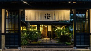 Un edificio japonés tradicional con un porche cubierto, un letrero con caracteres japoneses y un camino que conduce a la entrada.