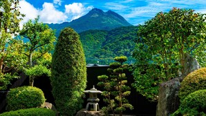 Un jardín sereno con una pagoda japonesa tradicional, abundante vegetación y una montaña al fondo.