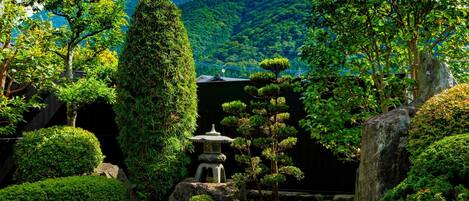 Un jardín sereno con una pagoda japonesa tradicional, abundante vegetación y una montaña al fondo.