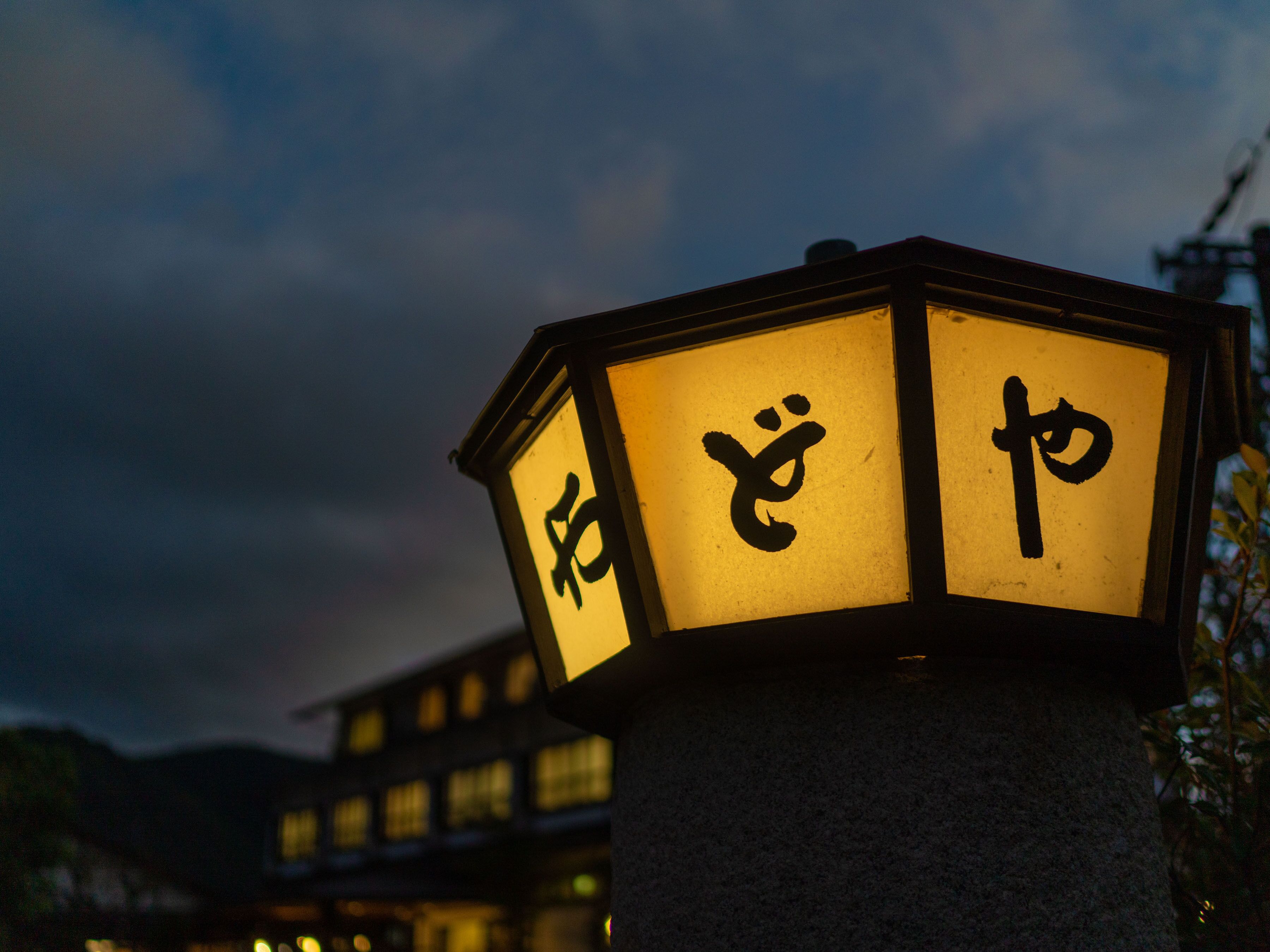 A traditional lantern with Japanese characters, mounted on a stone pillar.