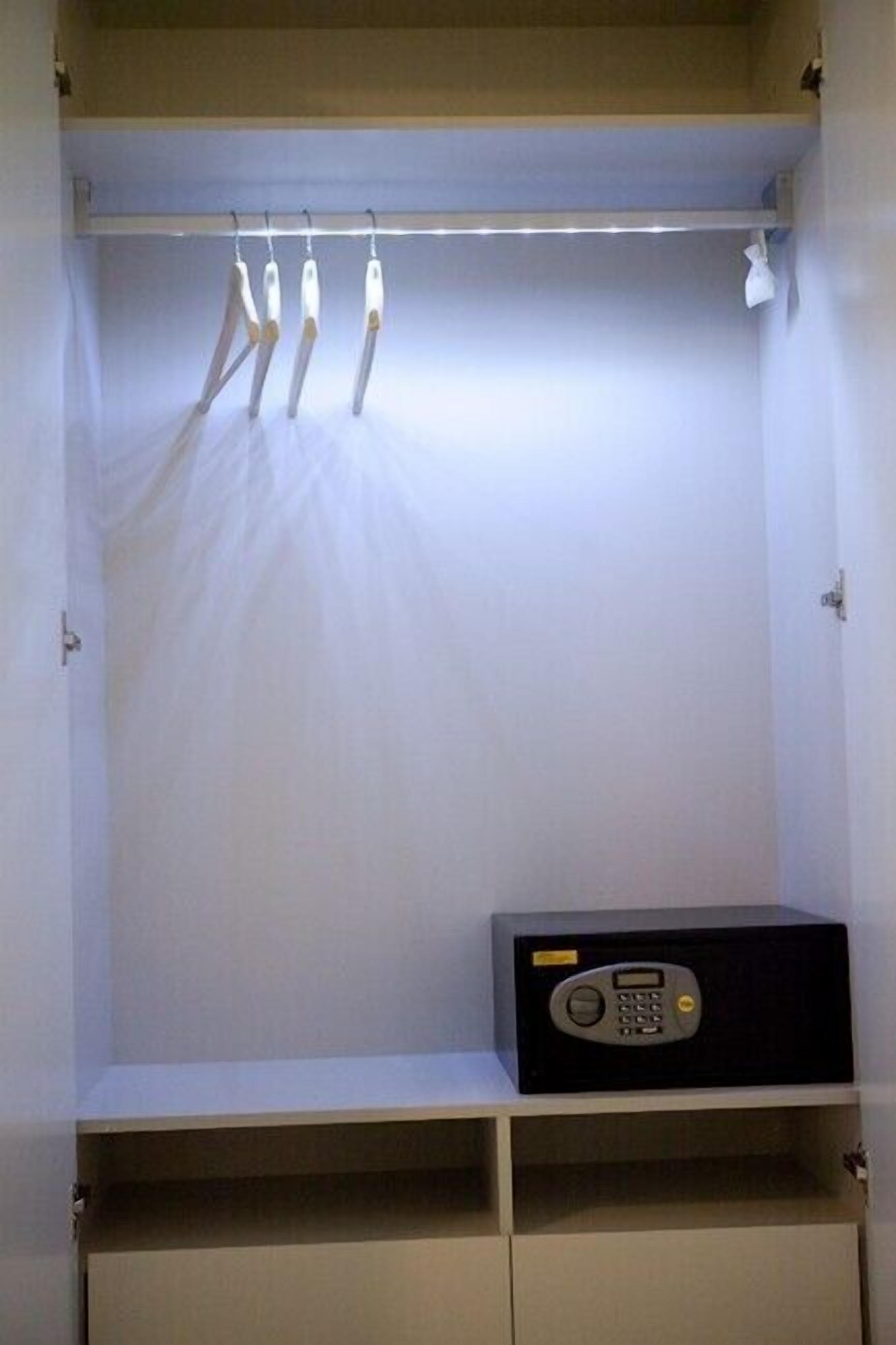 A closet with hanging clothes and a radio on the shelf.