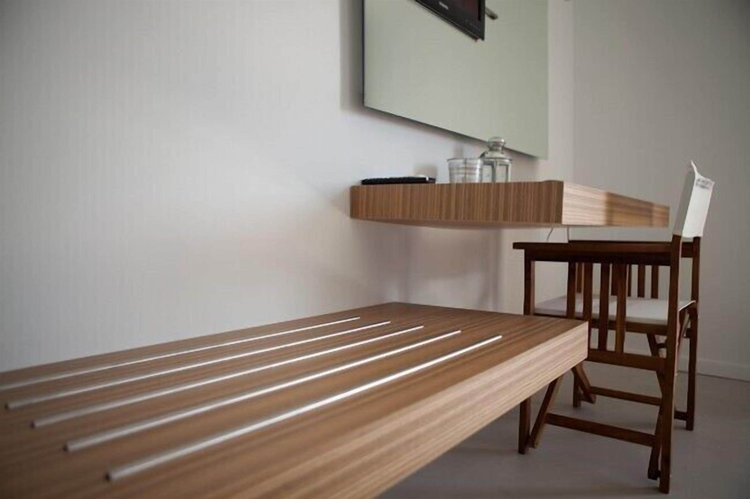 Una habitación minimalista con un banco de madera, una mesita y una silla.