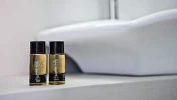 Dos botellas de perfume sobre una encimera de baño con un lavabo blanco al fondo.