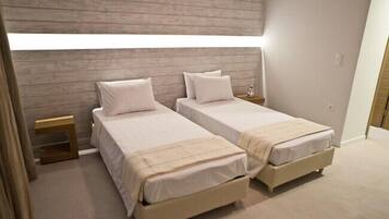 A bedroom with two beds, a wooden headboard, bedside tables, and a window.