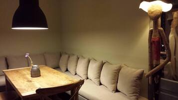 A corner seating area with a wooden table, a vase with a single flower, and a unique light fixture.