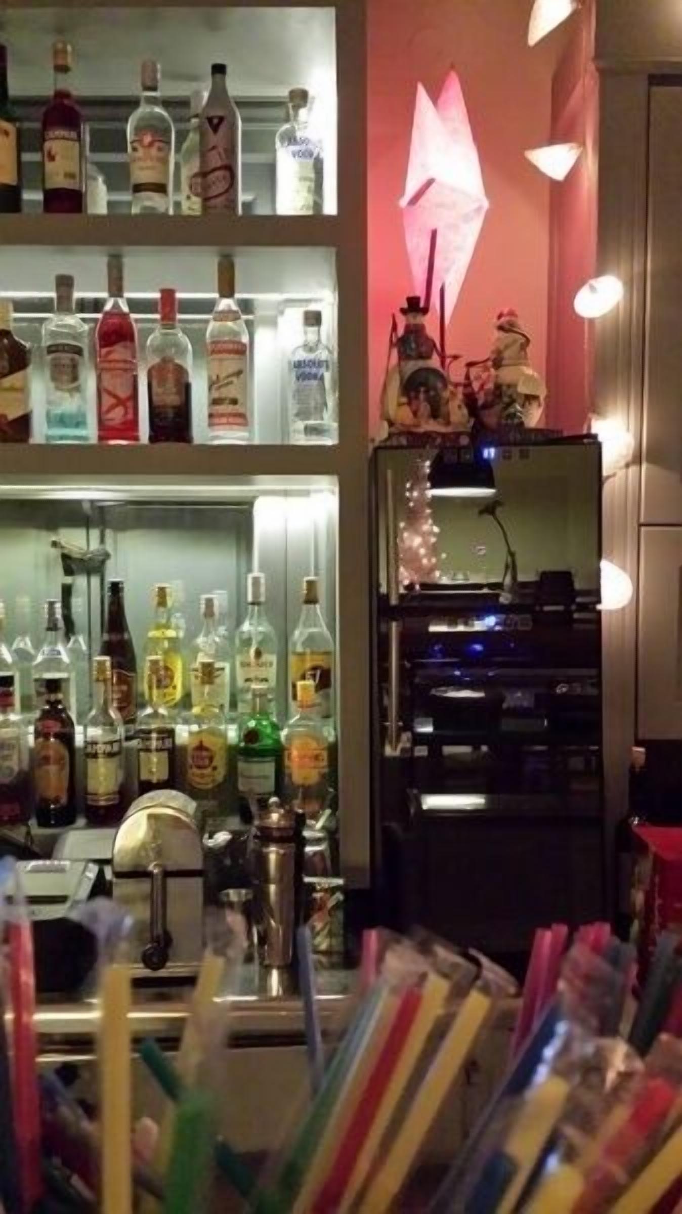 A bar area with shelves of liquor bottles, a neon sign, and a jukebox.