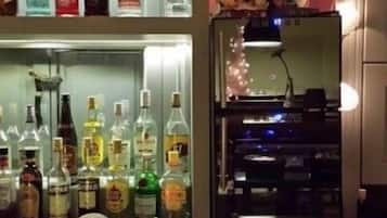 A bar area with shelves of liquor bottles, a neon sign, and a jukebox.