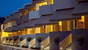 Een modern gebouw met een unieke geometrische gevel, meerdere balkons en een reeks treden die naar de ingang leiden.