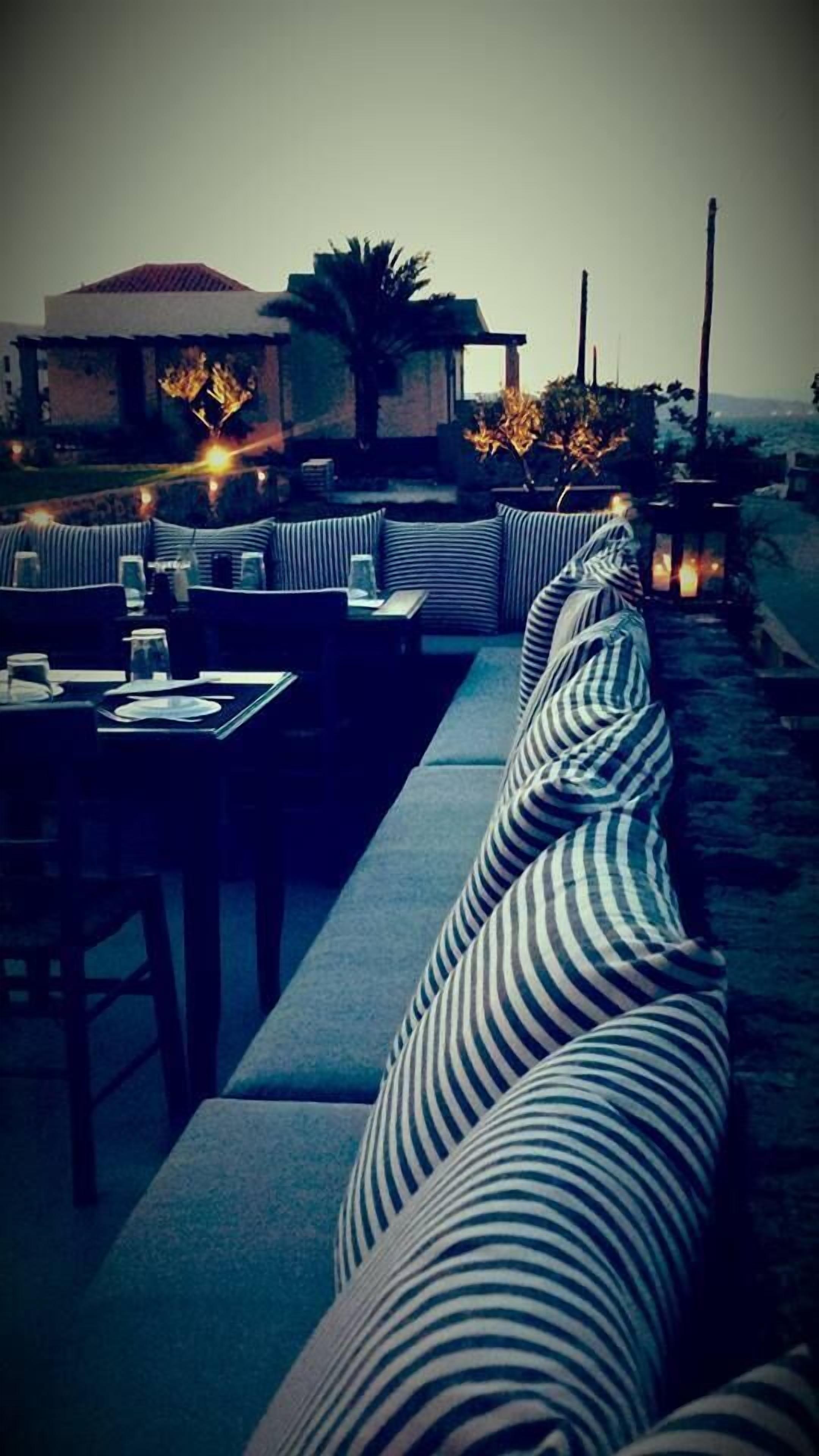 A restaurant with a long, striped sofa and tables set for dining.