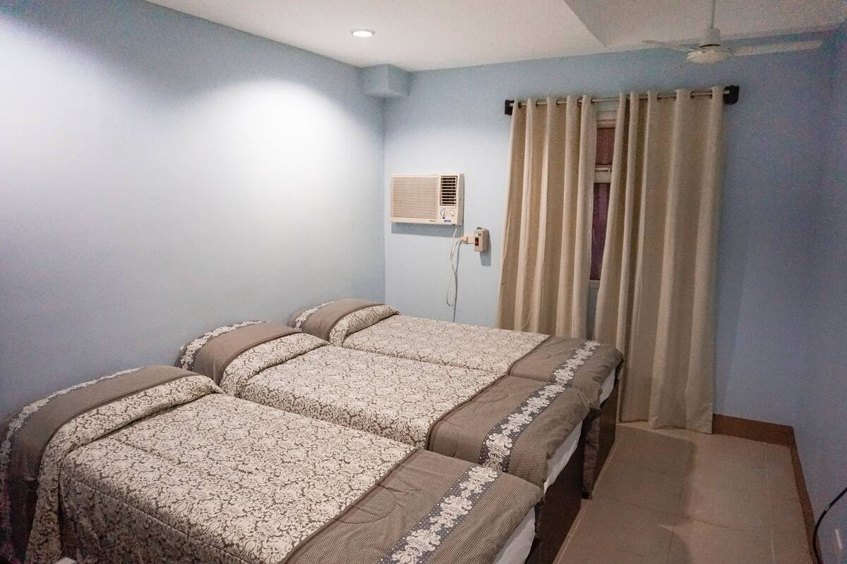 A bedroom with two beds, a ceiling fan, and an air conditioning unit.