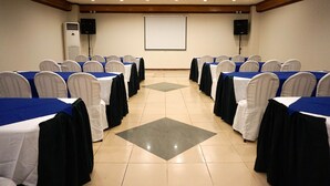 A conference room with tables arranged in rows, equipped with chairs and a projector screen at the front. - Crowne Garden Hotel (Cebu City)
