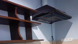 A kitchen with a granite countertop, a kettle, a built-in oven, and a shelf with dishes. - Crowne Garden Hotel (Cebu City)