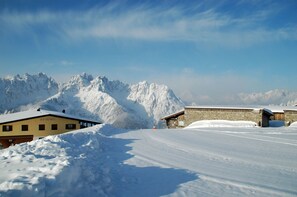 Un paisaje montañoso cubierto de nieve con un edificio de fachada de piedra y techo amarillo.