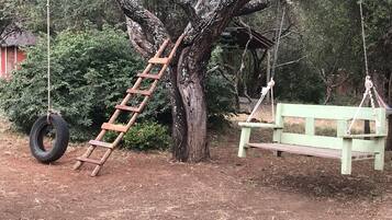 Relax in a serene outdoor setting with a charming wooden swing and ladder.