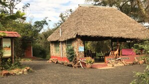 A thatched-roof structure with a sign reading "Welcome to Oloip." - Maasai Simba Camp (Amboseli)