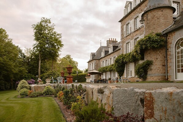 A stone building with a garden patio, outdoor seating, and a stone wall.