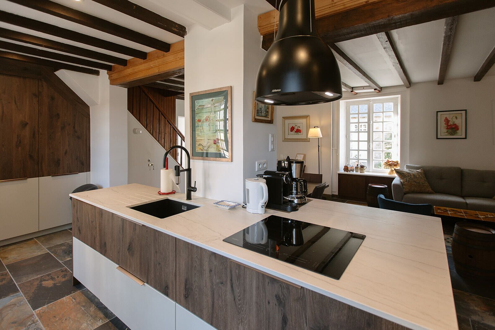 A kitchen with a central island, a coffee maker, and a sink.