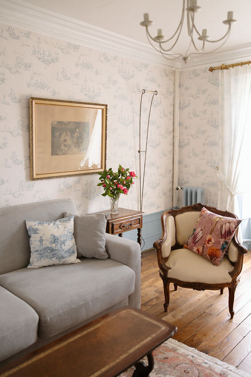 A living room with a sofa, armchair, wooden coffee table, and a framed picture on the wall.